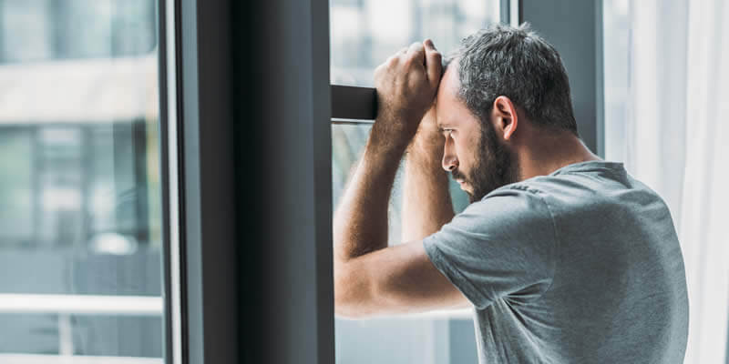 frustrated man locked in house staring out windows