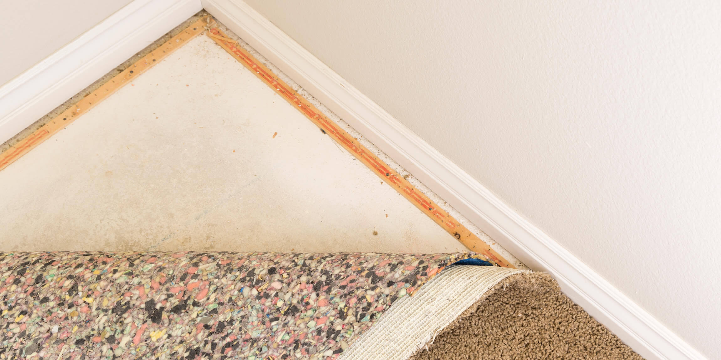 carpet pulled back revealing padding and nailer strips