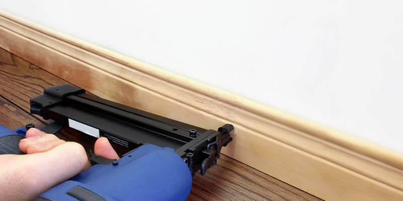 carpenter installing baseboard moldings