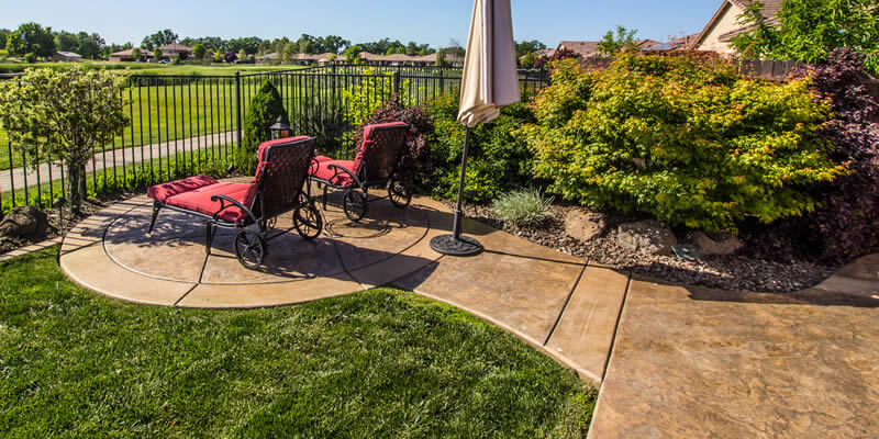 stamped concrete patio in backyard with lounge chairs