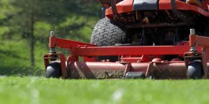 landscaper using a commercial mower to cut grass