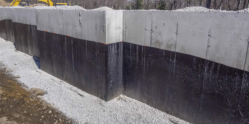 concrete foundation with waterproofing at grade and stones